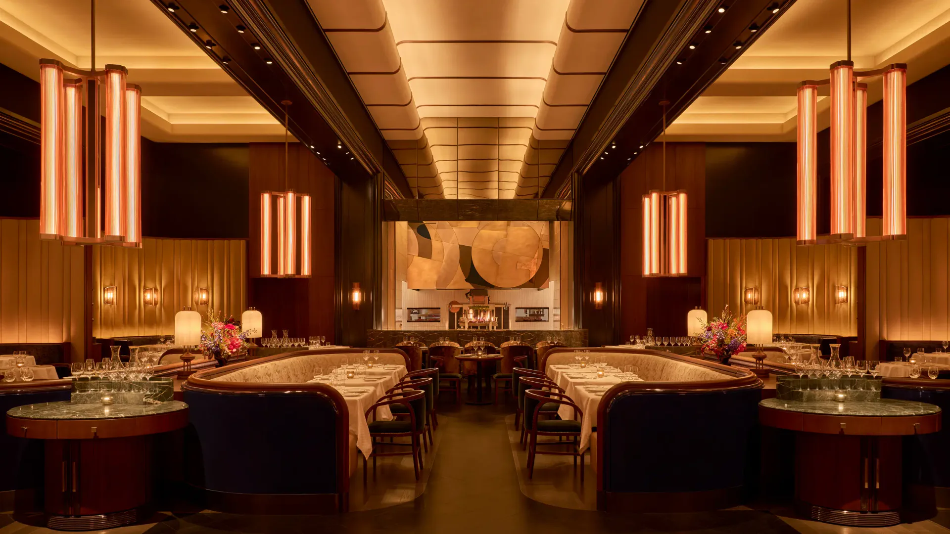 Elegant dining room with warm gold ceiling details, burgundy leather banquettes, and ambient lighting throughout by Rockwell Group.