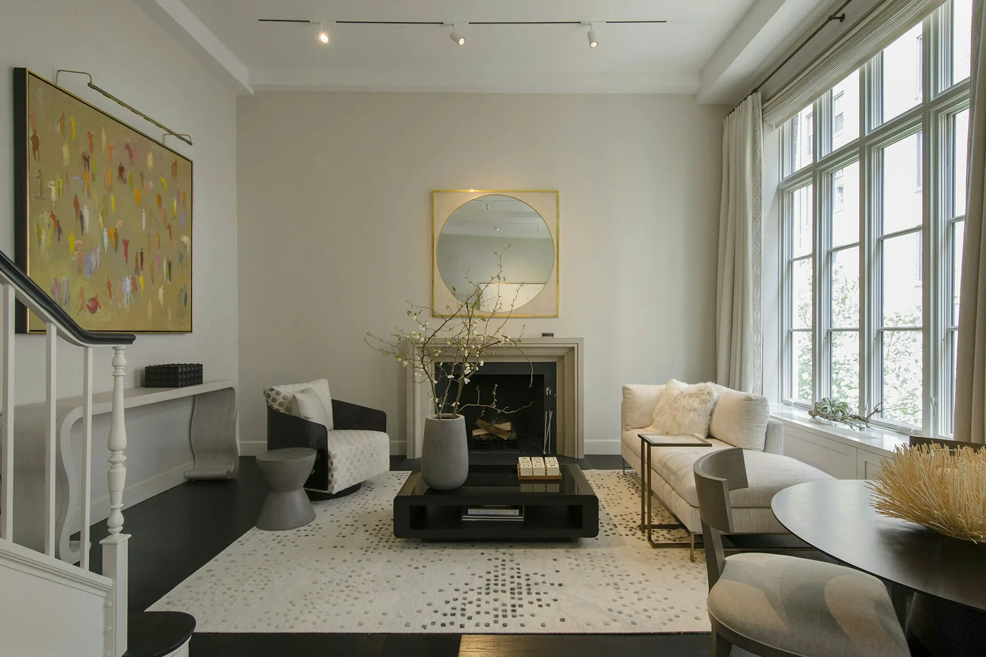 Modern living room with cream and black palette features geometric fireplace surround, large windows, contemporary furniture, and gold-framed artwork by Rodman Paul Architects, PLLC.