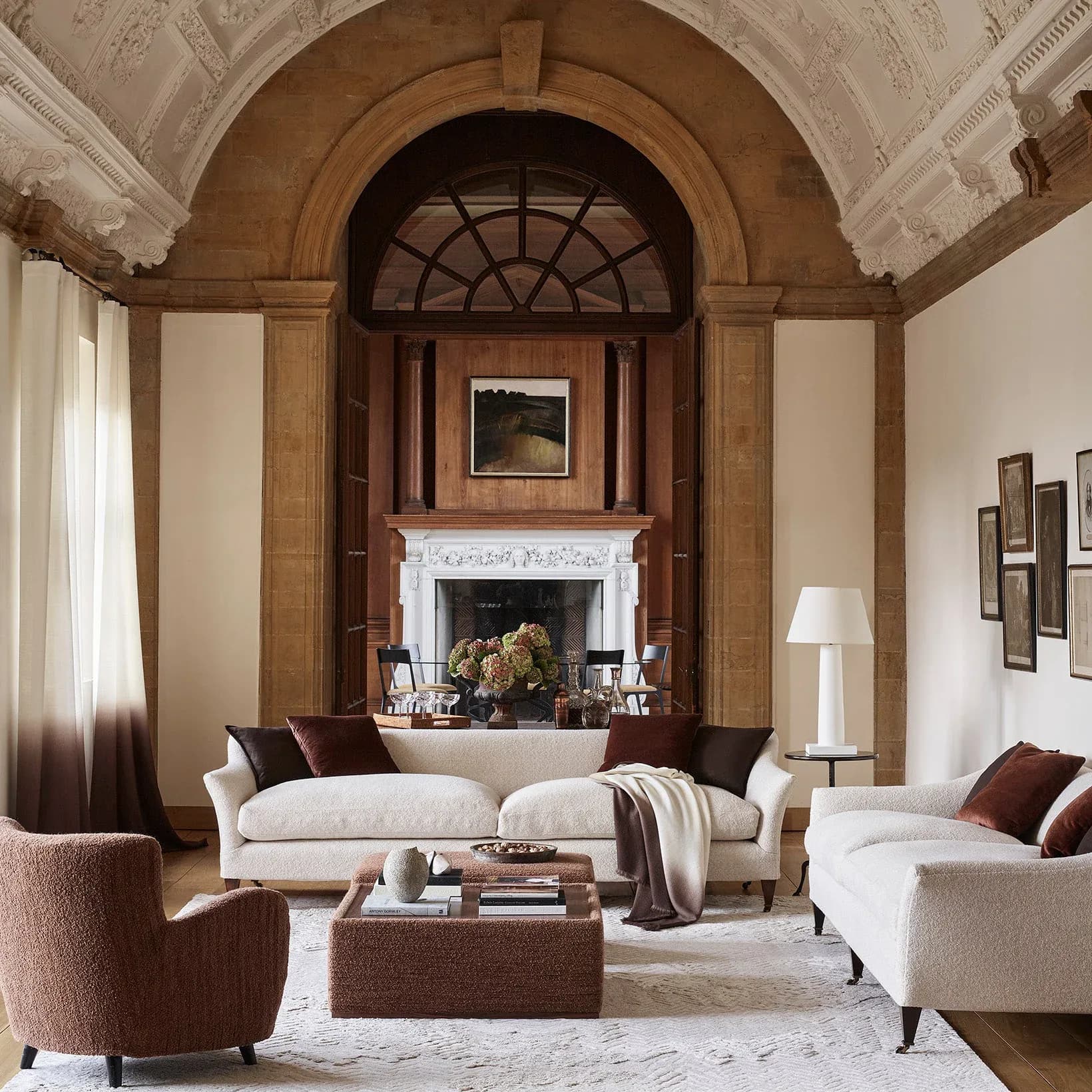 Elegant living room with cream sofas, arched wooden doorway, fireplace, and classical proportions by Rosemary Hallgarten.