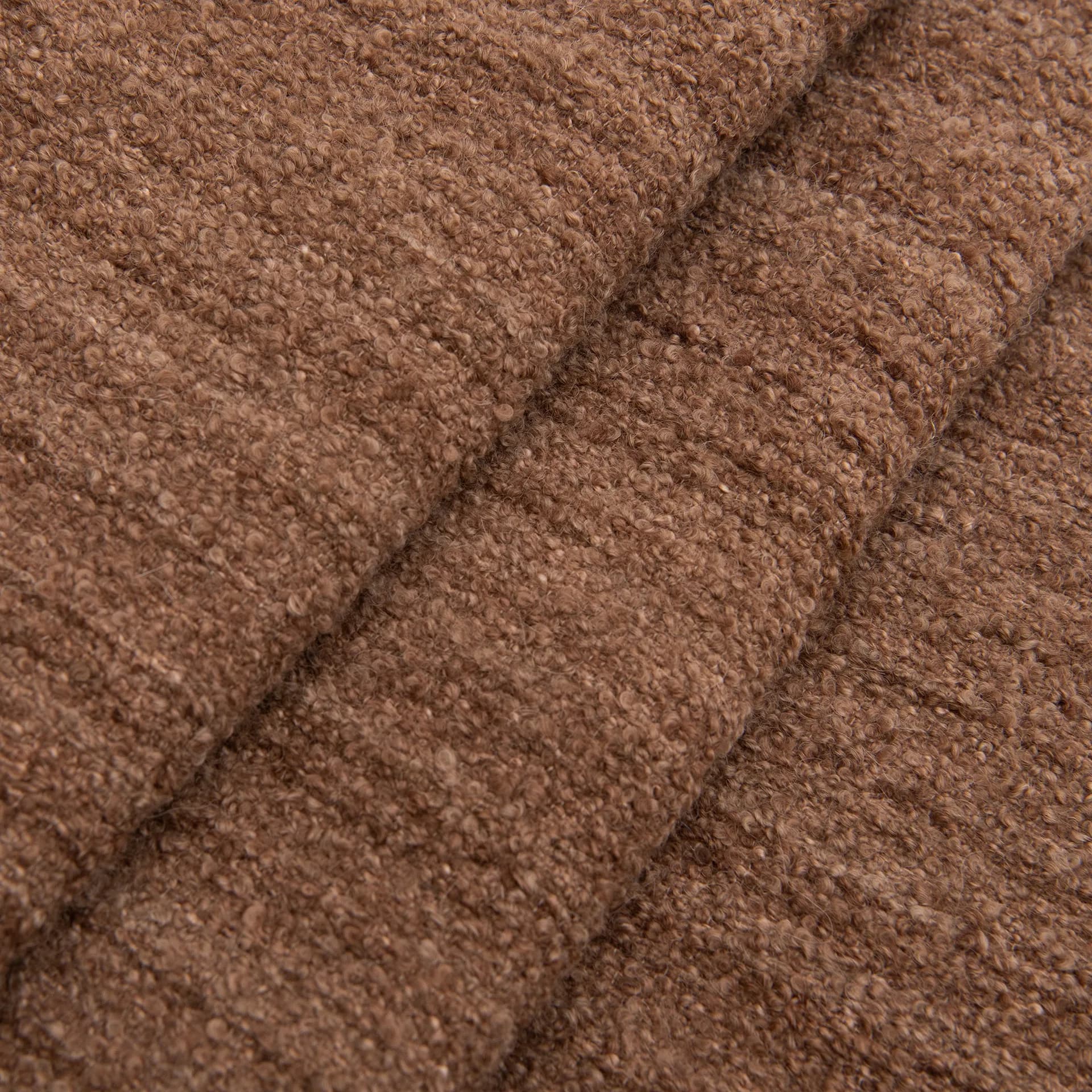 Close-up detail of warm taupe upholstered fabric with diagonal seaming and soft texture, showcasing material selection and craftsmanship by Rosemary Hallgarten.
