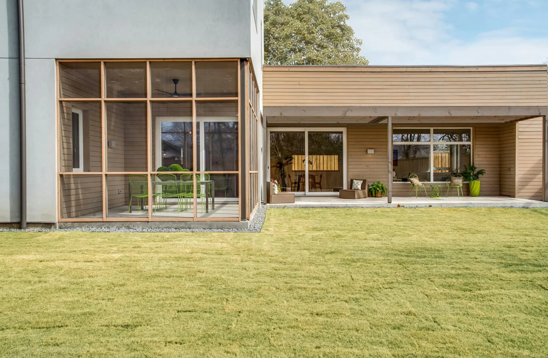 Modern residential architecture with white and timber-clad facades, large glazed courtyard opening onto manicured lawn by Ryall Sheridan Architects.