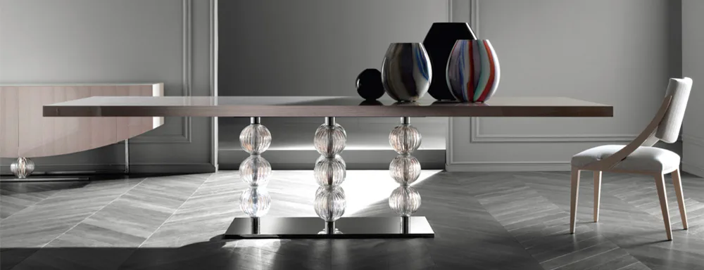 Modern minimalist dining space with glass-top table, chrome pedestals, and contemporary chairs in a neutral palette with gray flooring by S & G Fine Chair Collection, Inc.