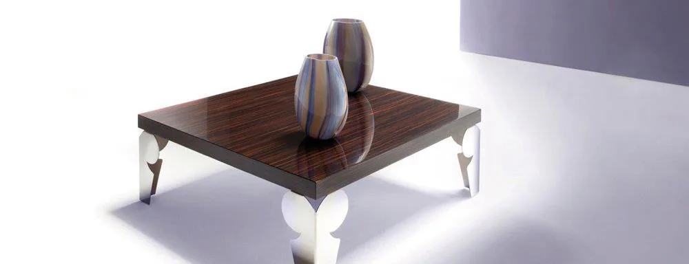 Modern coffee table with dark wood top and white sculptural legs, styled with gray headphones, rendered with idealized lighting and proportions by S & G Fine Chair Collection, Inc.
