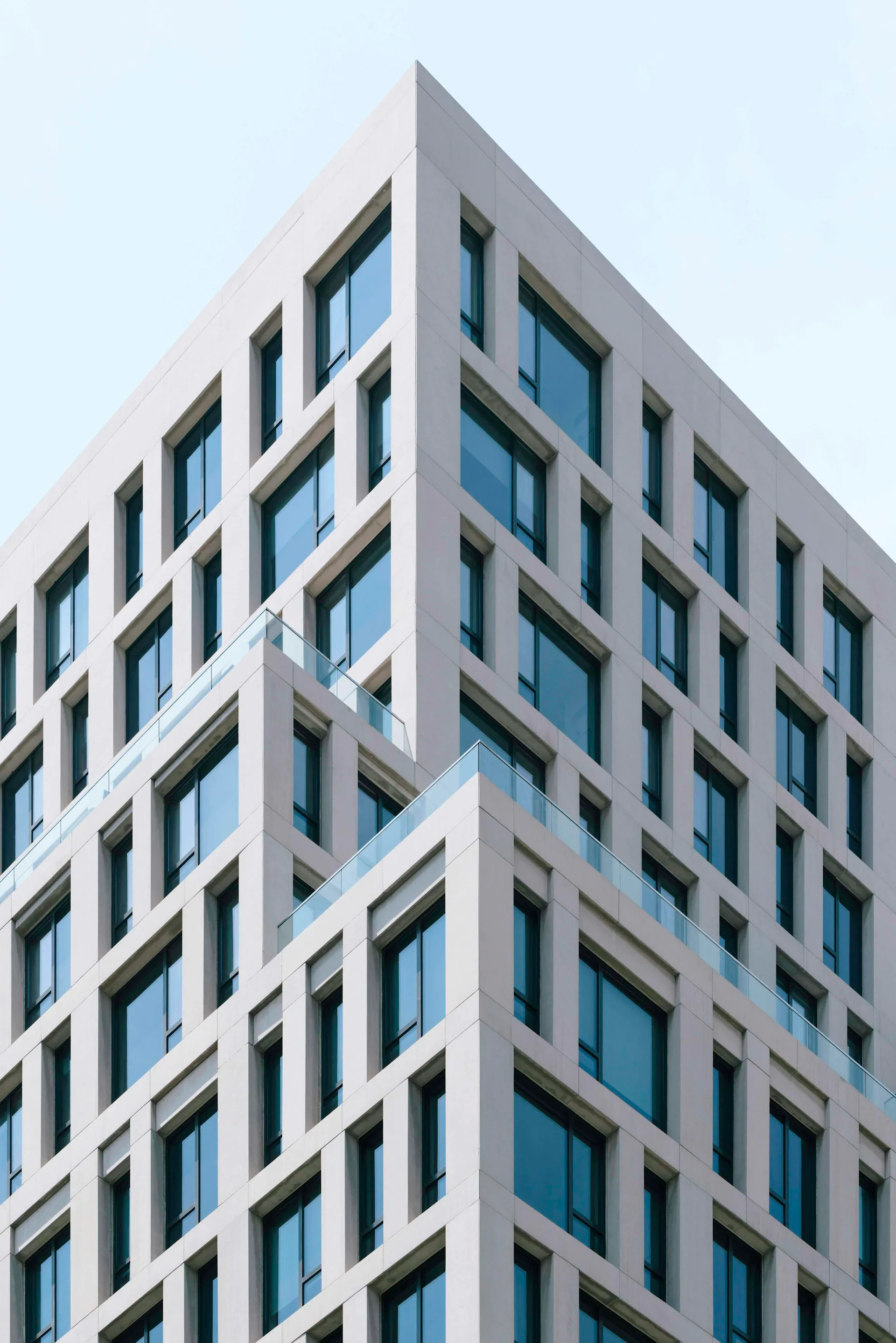 Contemporary residential building facade with repetitive window grid, white concrete frame, and blue-tinted glazing by S9ARCHITECTURE.
