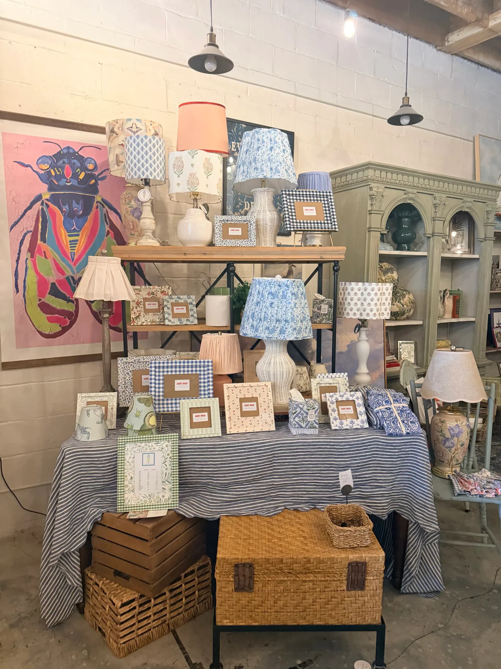 Retail display with wooden shelving, patterned lampshades, decorative boxes, and home accessories in blue and cream tones by Saint Malo Designs.