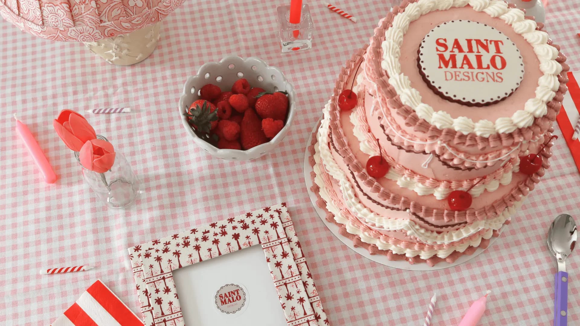 Pink and white tiered cake with beaded detailing displayed on gingham tablecloth with coordinating party styling by Saint Malo Designs.