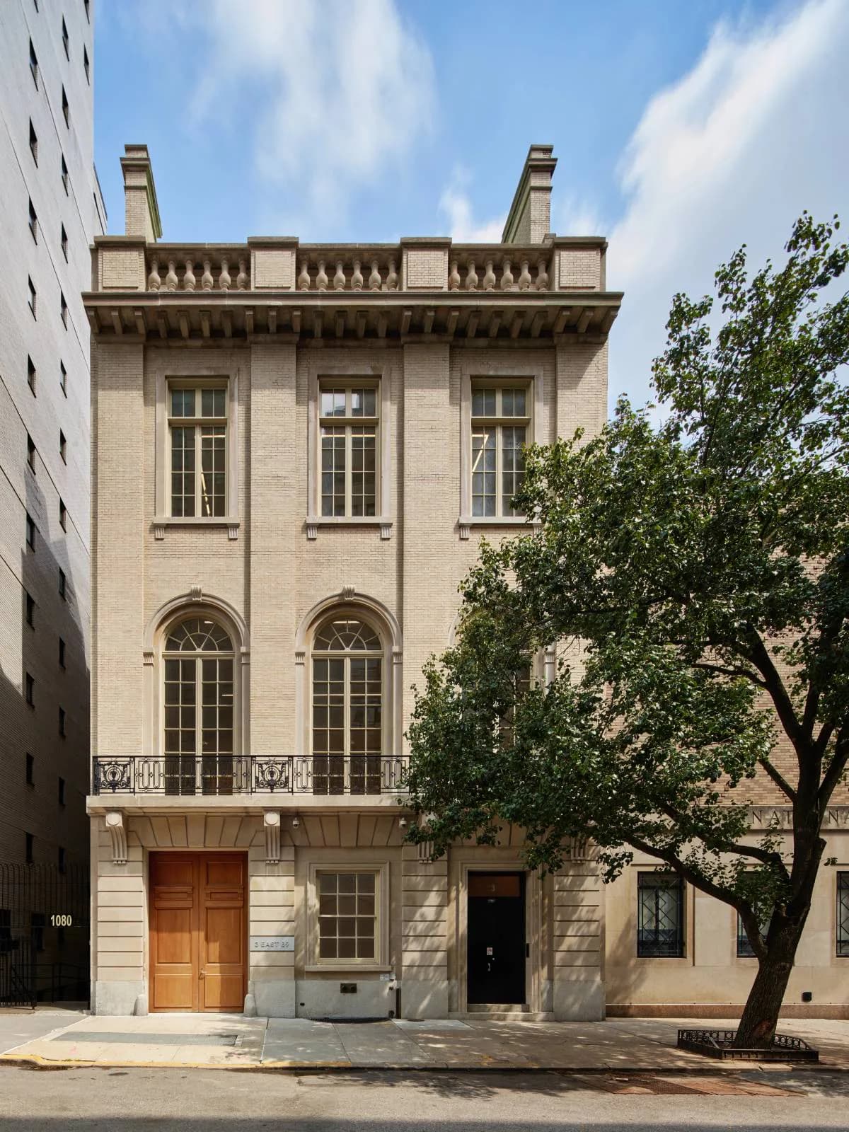 Neoclassical building facade with cream-colored stone, tall arched windows, and ornamental cornice detail, photographed in daylight by Salon 94 Design.