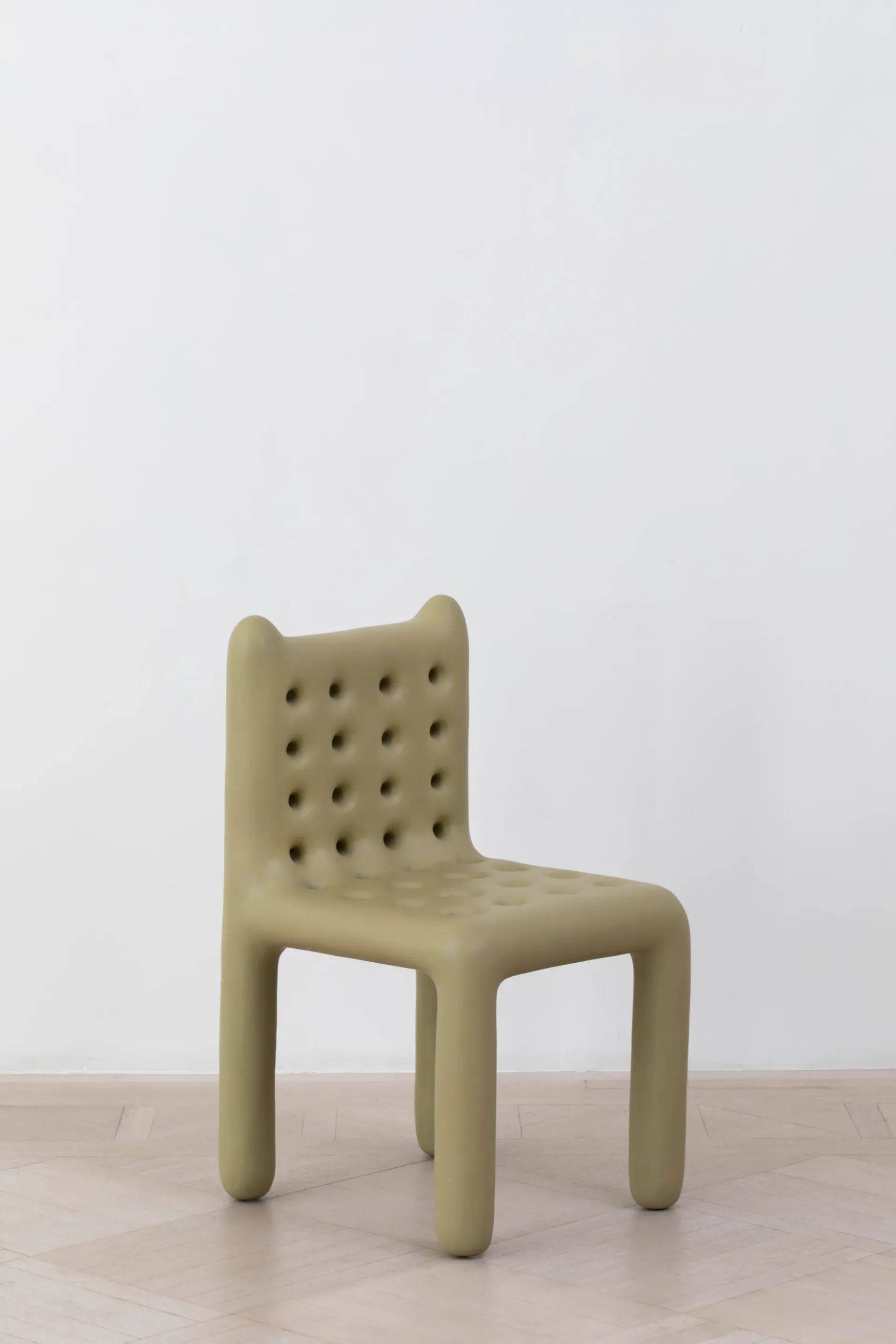 Pale green sculptural chair with rounded forms and quilted backrest detail sits on light wood flooring against white wall by Salon 94 Design.