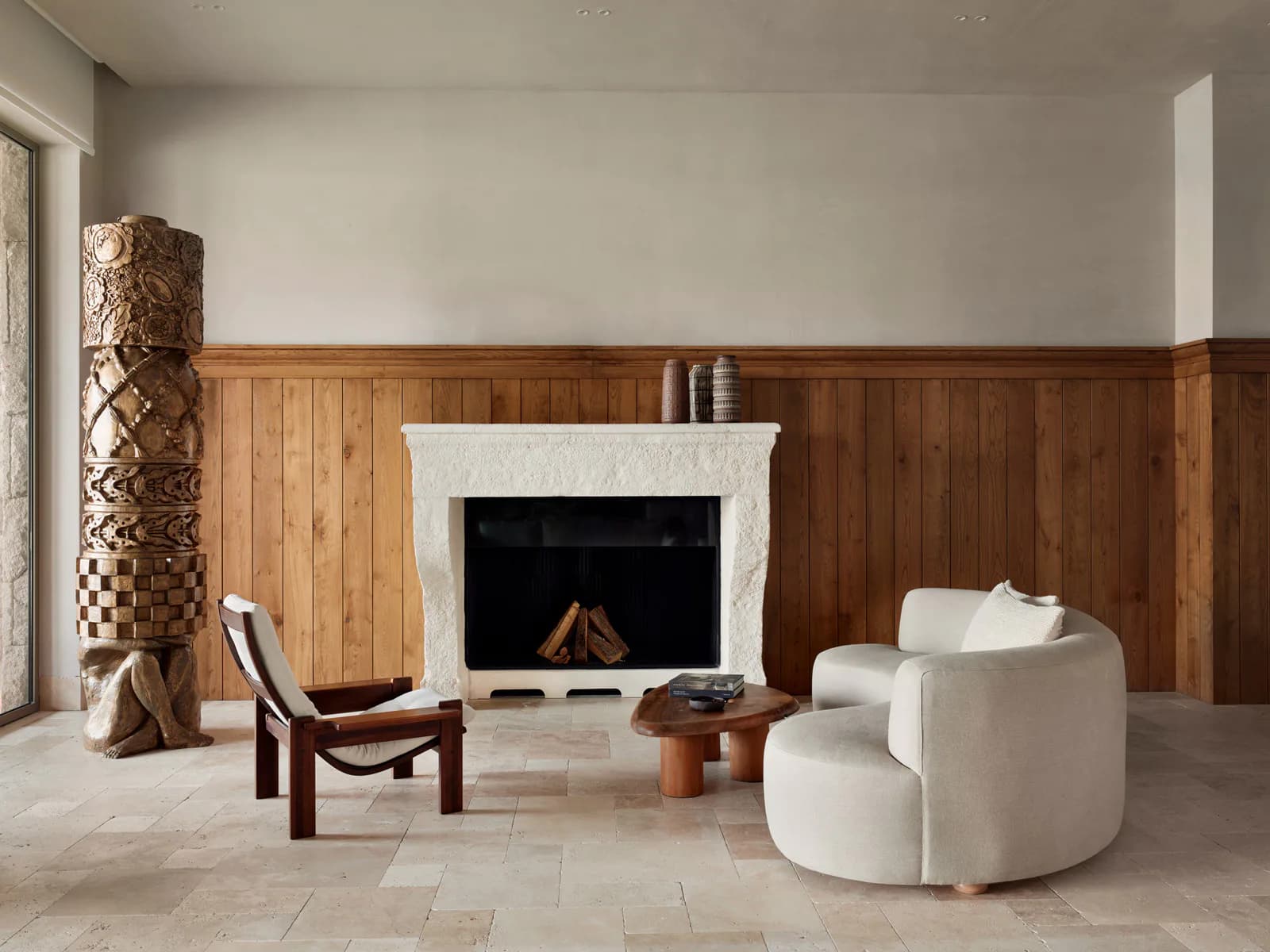 Minimalist living room with wooden wall paneling, white fireplace, curved cream furniture, and warm wooden accents designed by Sanayi313.