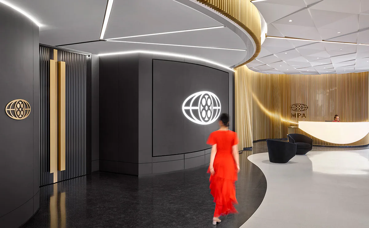 Modern corporate lobby with curved gold ceiling elements, black walls, and a figure in red; sleek minimalist interior by SBLD Studio.