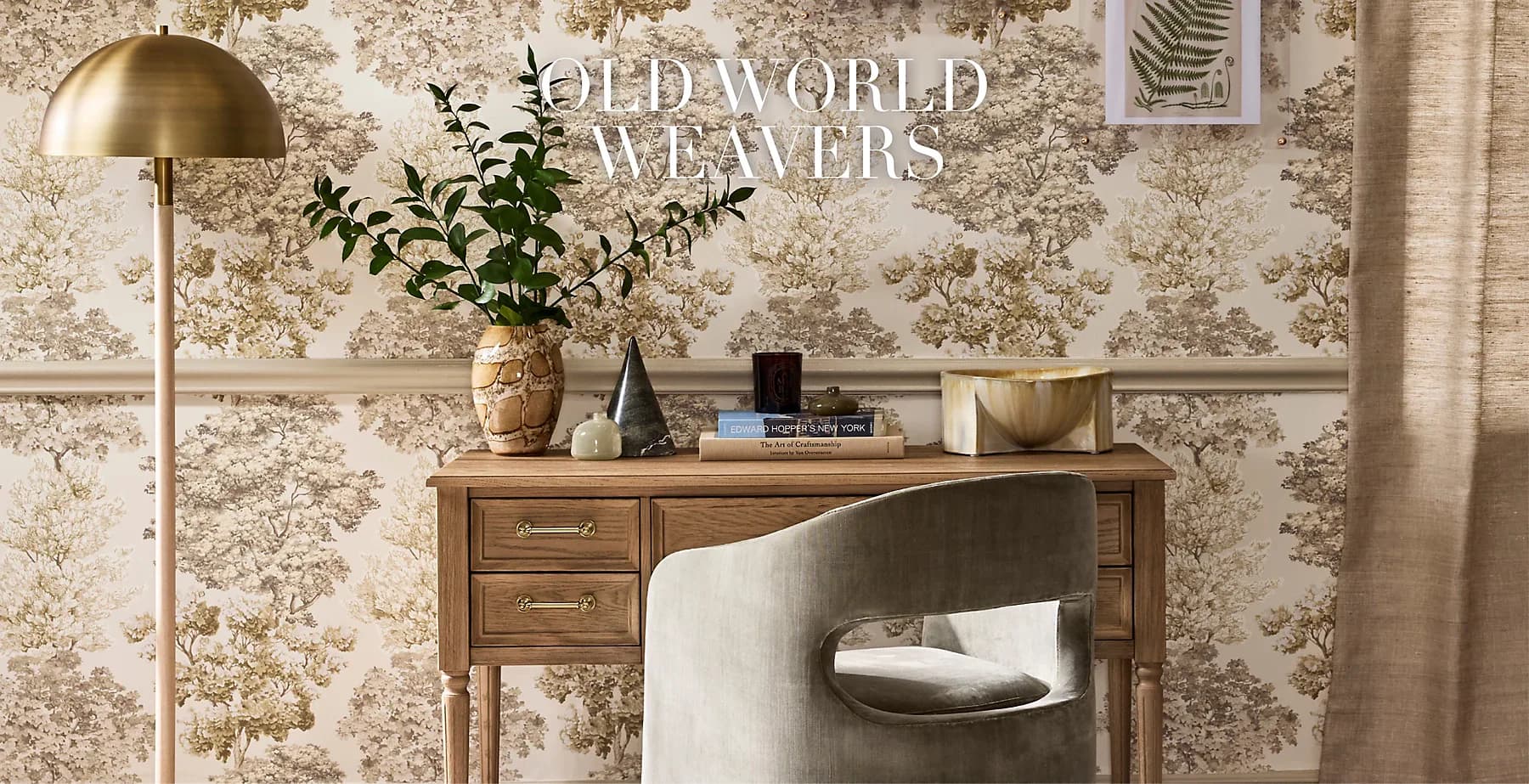 Warm-toned bedroom workspace with floral wallpaper, wooden desk, brass floor lamp, and styled accessories by Scalamandré.