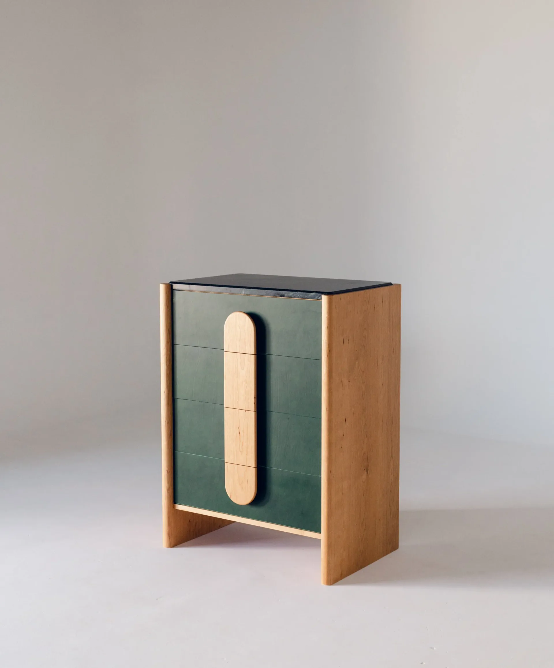 Wooden storage cabinet with dark green tiled interior panel and cream-colored cylindrical wooden element, featuring black top and natural wood sides, by Scheibe Design.