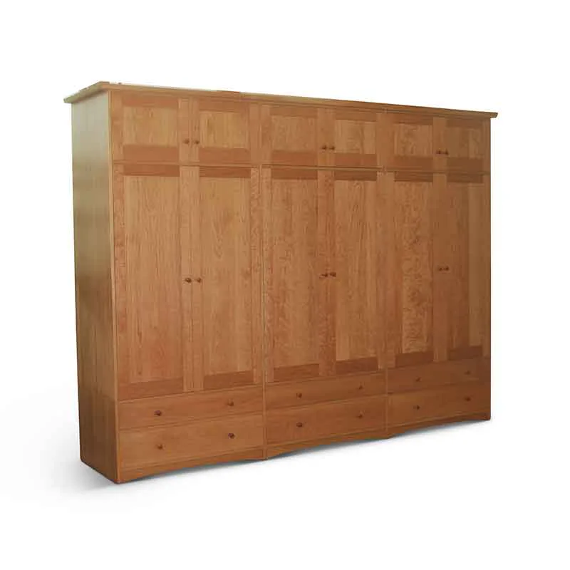 Large wooden wardrobe cabinet with multiple doors and drawers in warm cherry wood tones, featuring inset paneling and metal hardware by Scott Jordan Furniture.