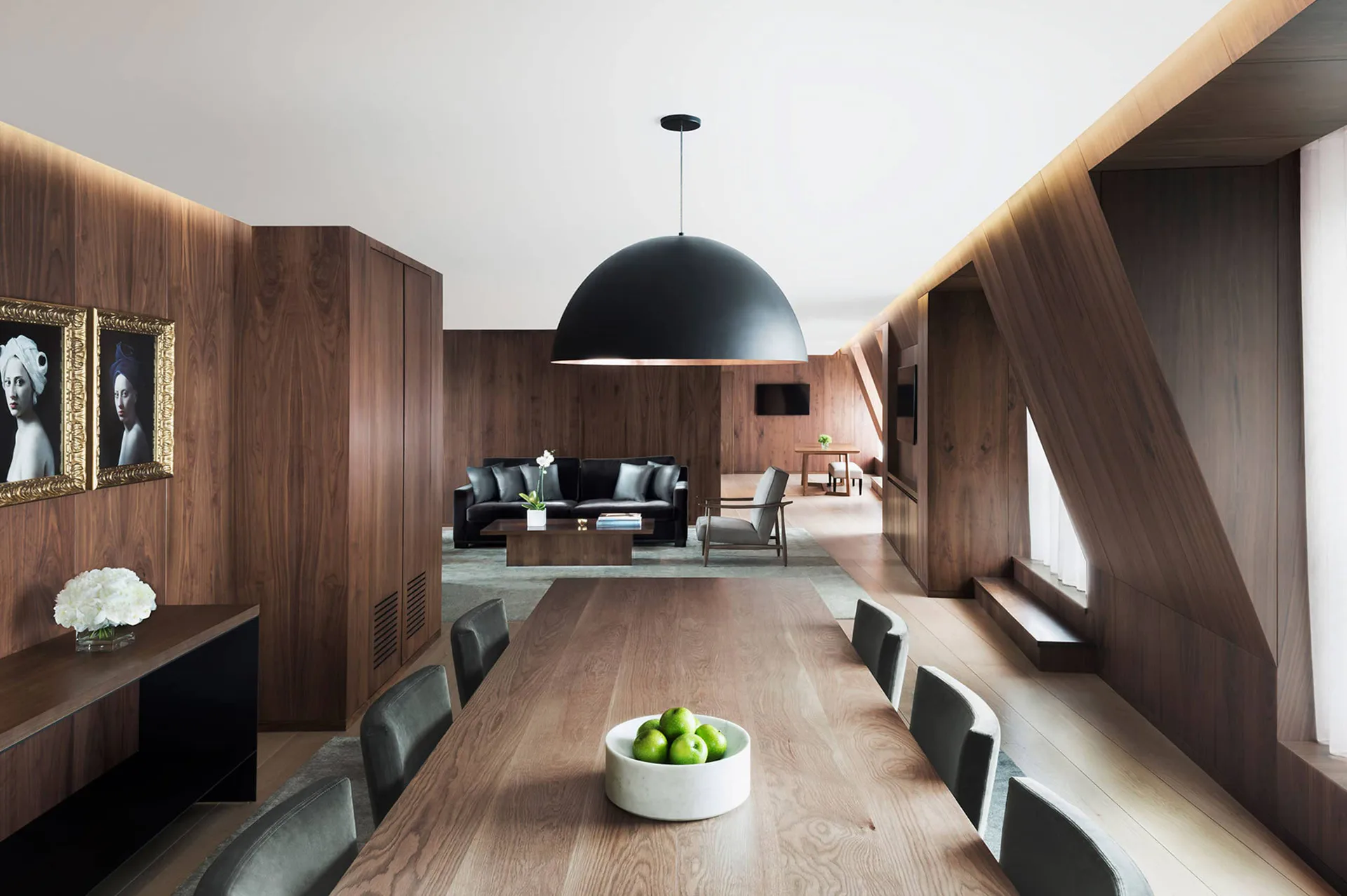 Modern interior with dark wood walls, long dining table, and dramatic black dome pendant light by SENTIENT.