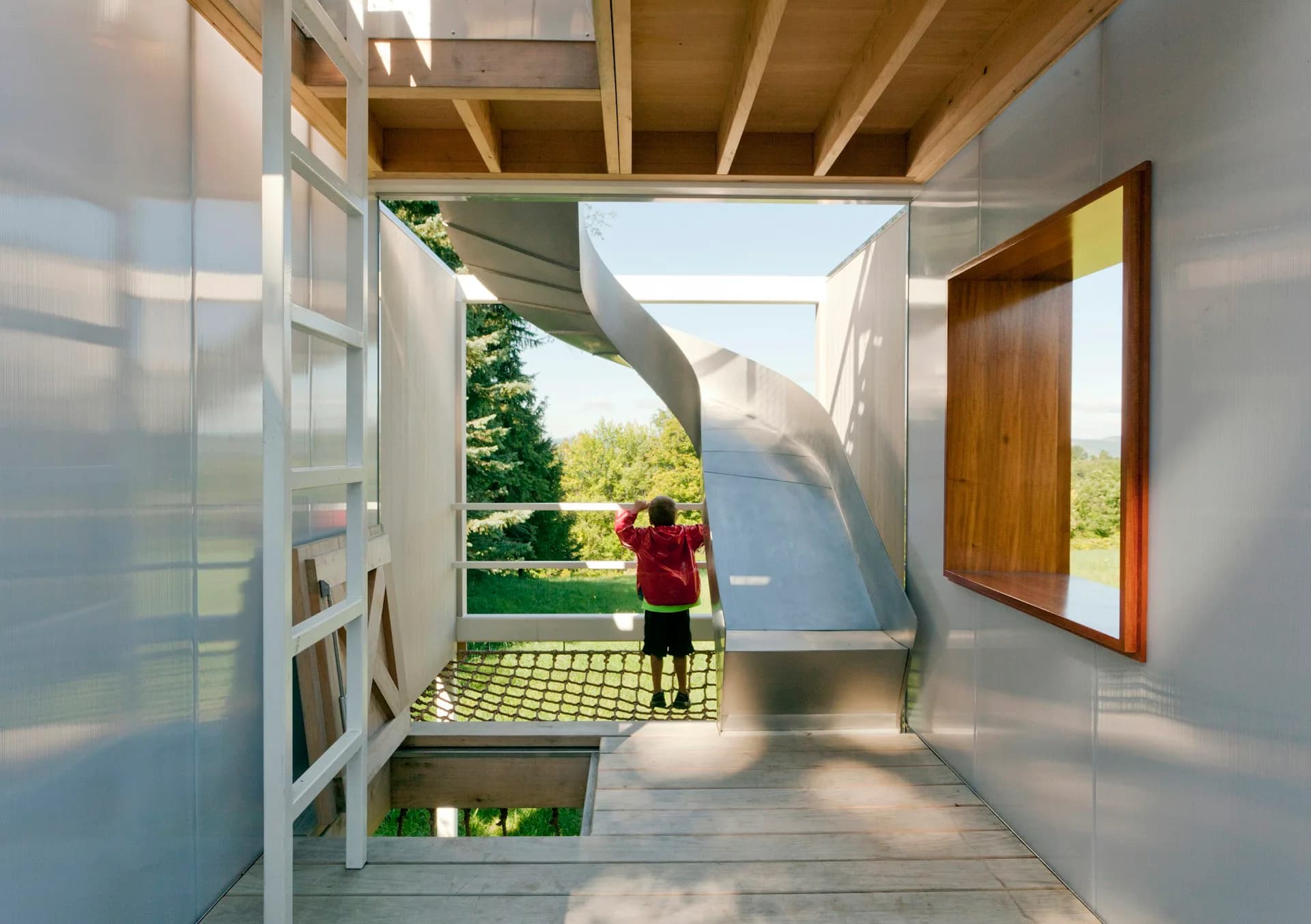Modern pavilion interior with white walls, wood ceiling, and glazed openings framing views of green landscape, by Sharon Davis Design.