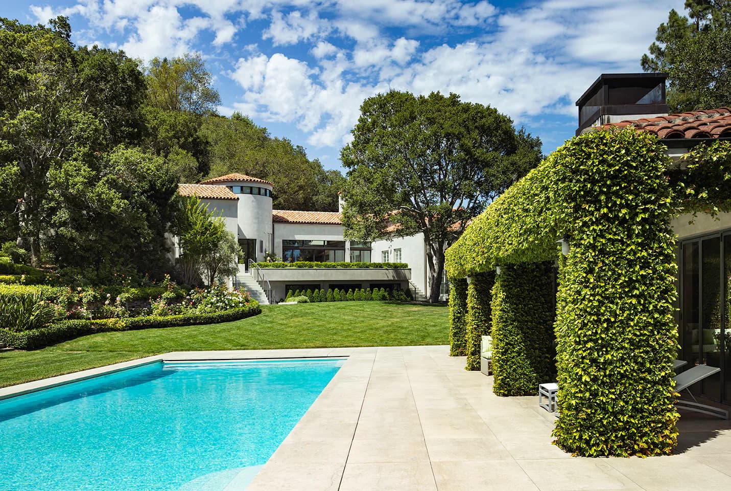 Modernist residential landscape featuring a turquoise swimming pool, manicured lawn, ivy-covered walls, and contemporary architecture with natural wood accents by SheltonMindel℠.