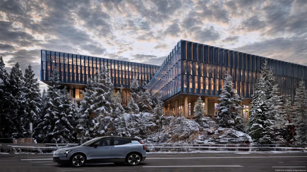 Modern angular building with dark vertical louvers surrounded by snow-covered evergreens, a silver vehicle parked in front, dramatic clouded sky above, by SHoP Architects.