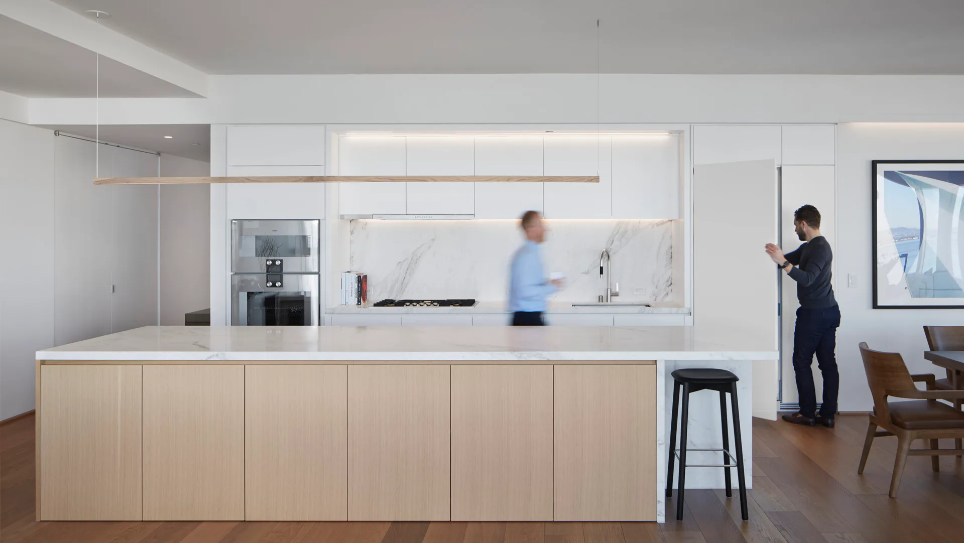 Modern office kitchen with light wood cabinetry, white countertops, and glass partition walls, featuring minimalist design by Skidmore, Owings & Merrill.