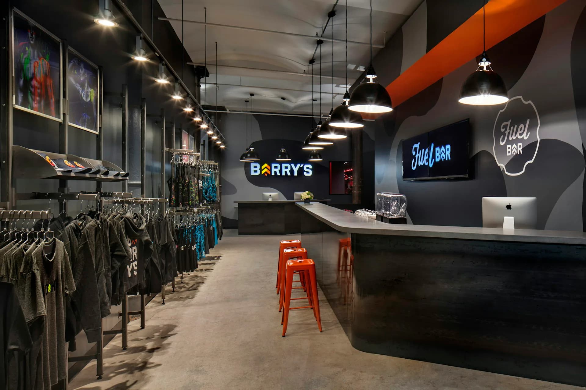 Modern retail interior with concrete flooring, black counter, clothing racks, neon signage, and orange structural beams by Smith and Architects.