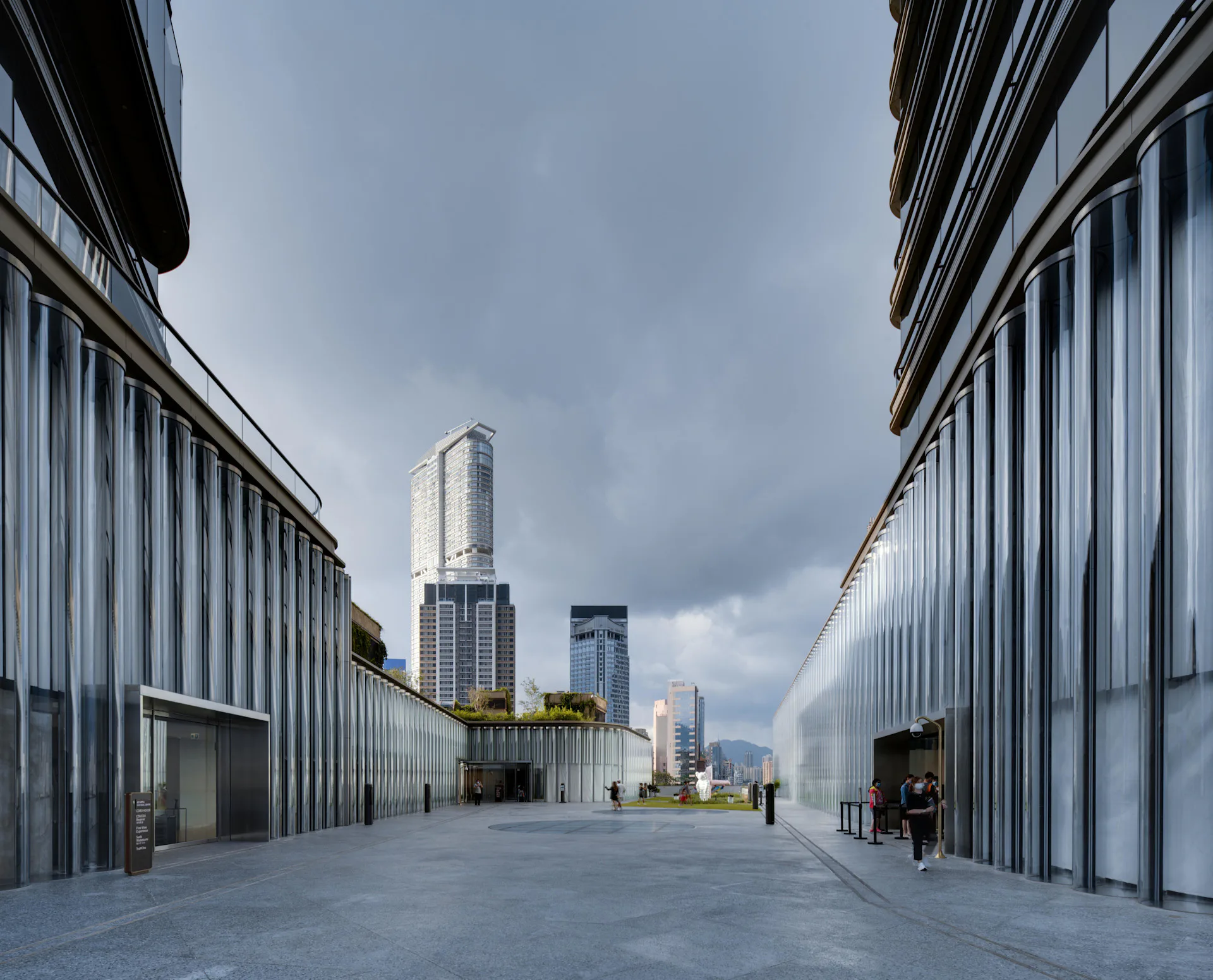 Contemporary industrial courtyard with symmetrical corrugated metal facades, polished concrete floor, and Manhattan skyline beyond by SO-IL.