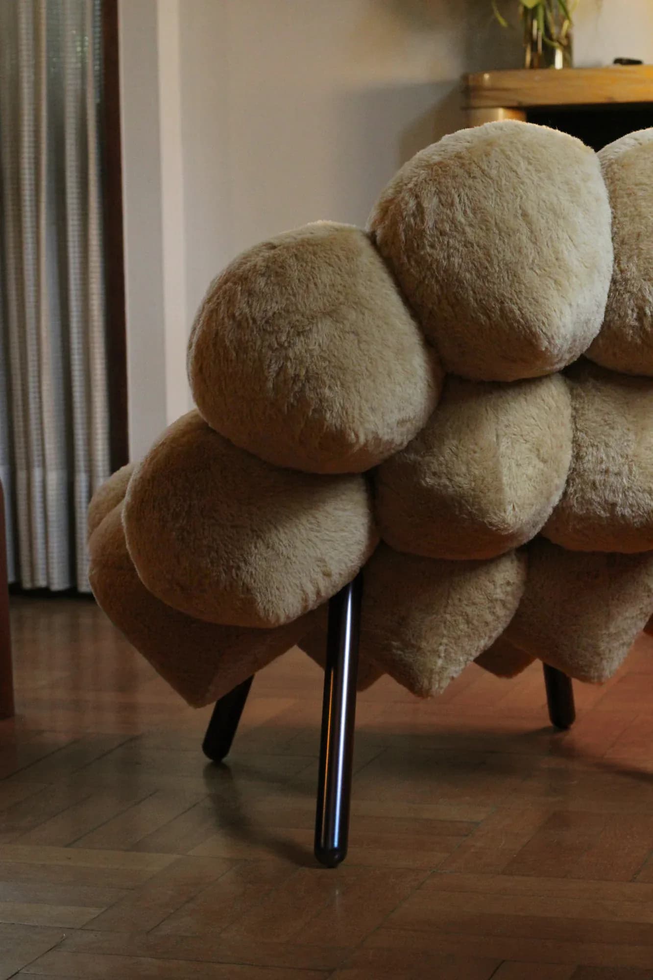Sculptural armchair with oversized rounded wool cushions in cream and beige tones on metal legs, positioned in a minimalist interior by Soft Witness.