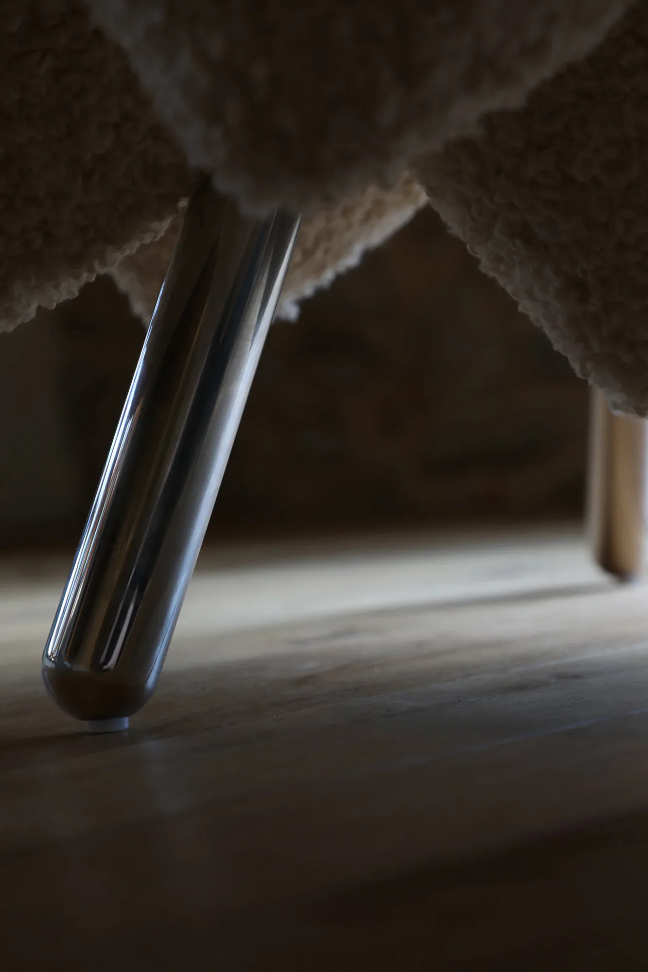 Minimalist interior detail featuring polished metal cylindrical elements and draped fabric against concrete surfaces, creating geometric shadows by Soft Witness.