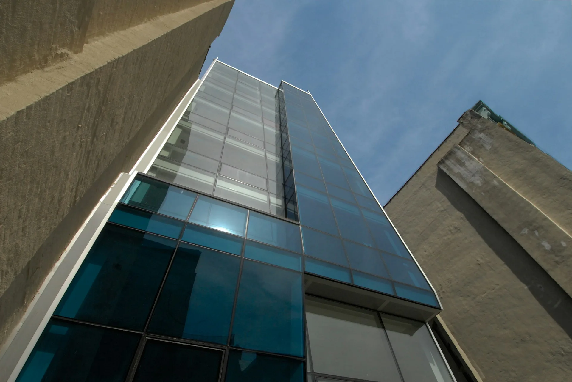 Modern glass and concrete tower facade photographed from below against blue sky, showcasing contemporary architectural design by Soluri Architecture.