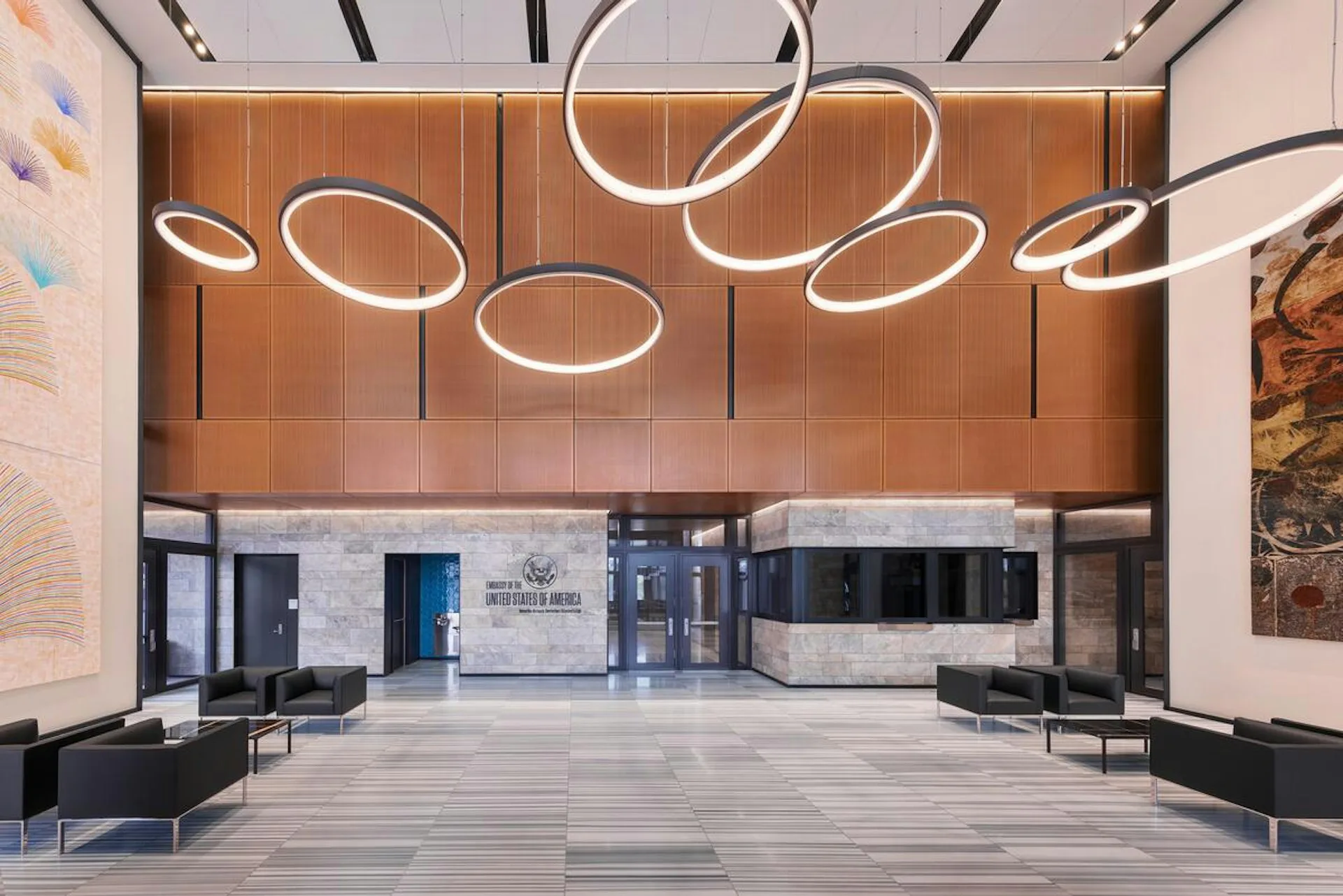 Modern lobby with wood paneled ceiling, sculptural white neon light installations, polished concrete flooring, and minimalist seating by Spacesmith.