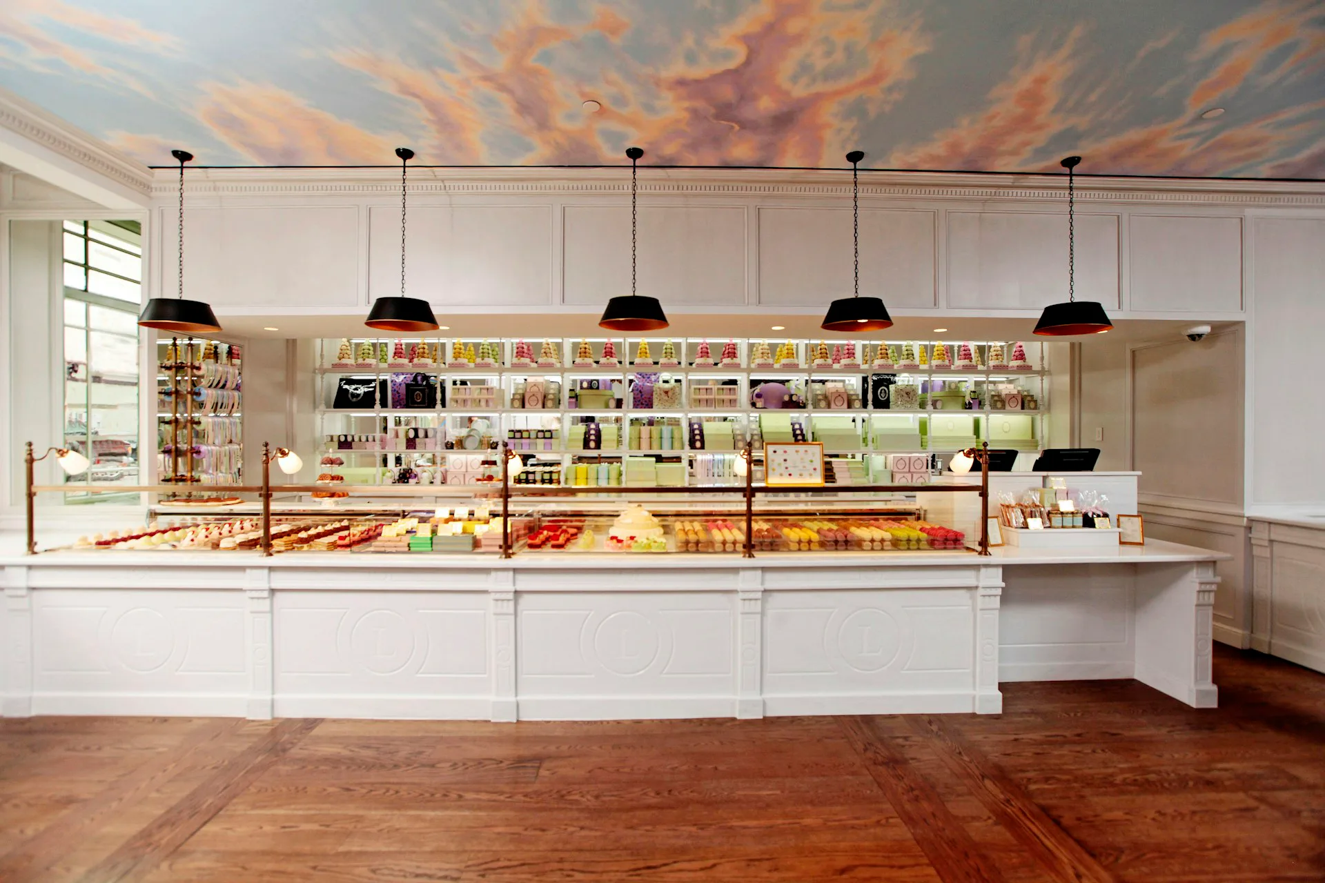 Modern retail bookstore with white cabinetry, long service counter, pendant lighting, and extensive shelving throughout, designed by Spacesmith.