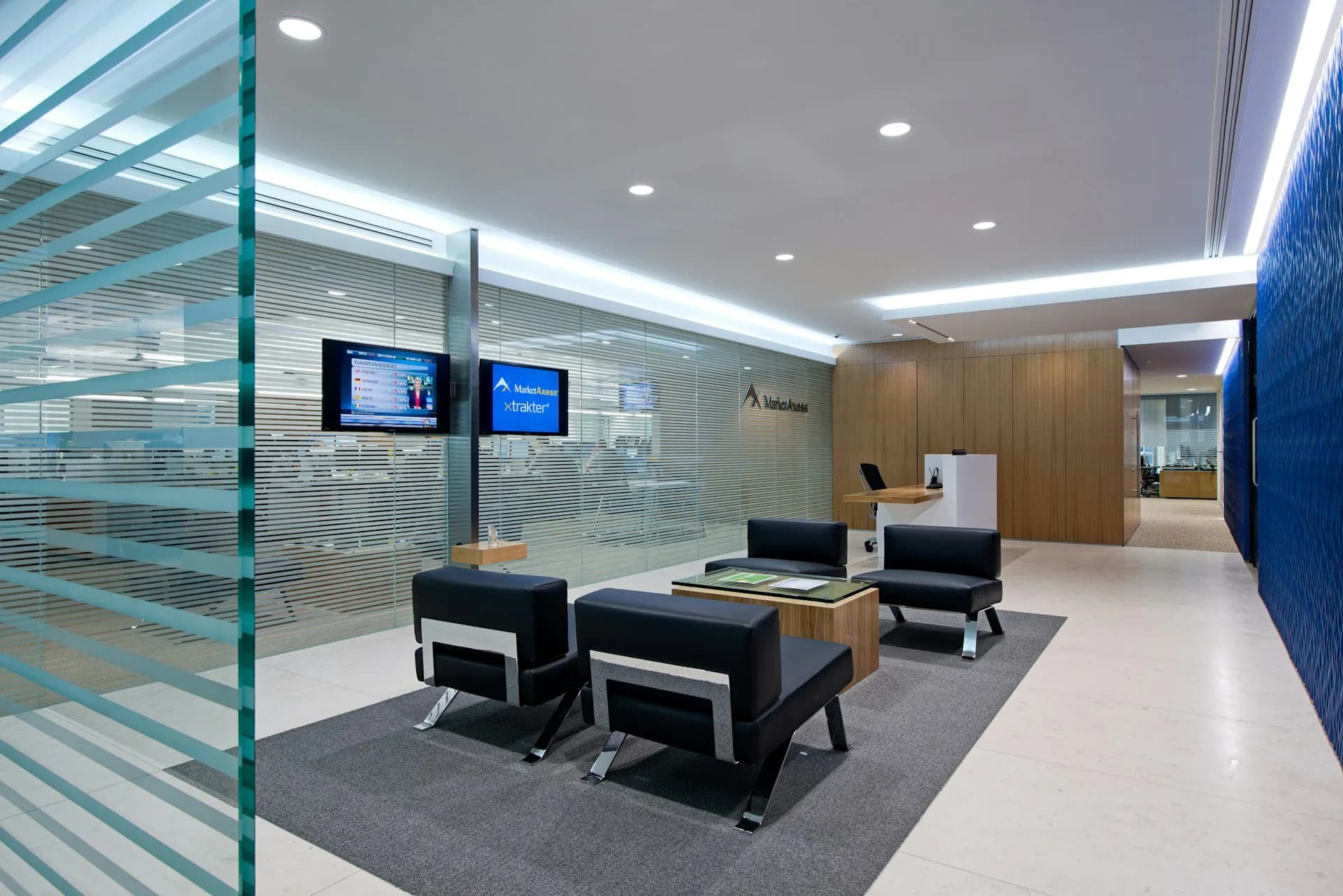 Modern office reception area with glass partitions, wood accents, and blue wall panels, designed by Spacesmith.