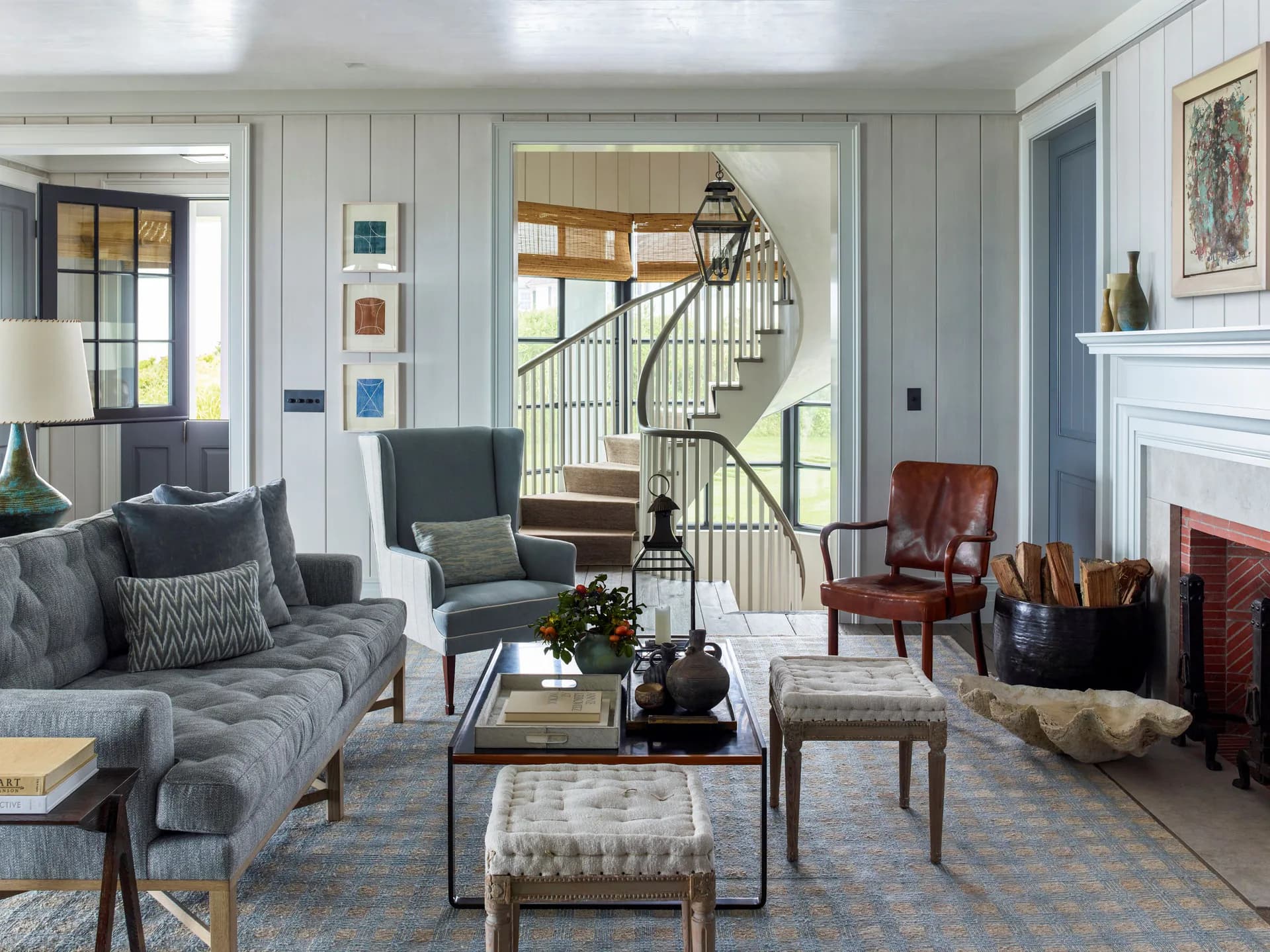 Elegant living room with gray upholstered seating, wood-framed staircase, fireplace, and neutral palette by S.R. Gambrel.