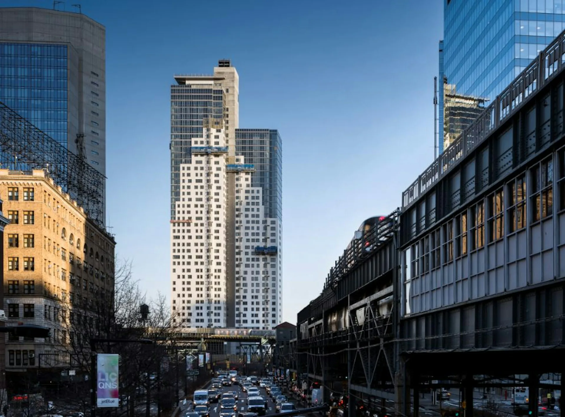 Urban street view with modern high-rise buildings and classical architecture under clear blue sky, designed by SBJ Group.