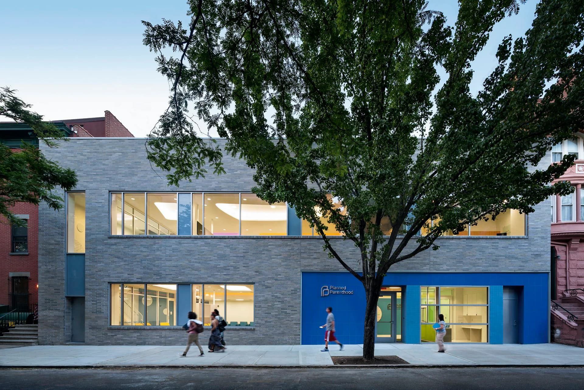 Contemporary blue-and-gray brick facade with large windows, mature tree, and street-level entrance, designed by Stephen Yablon Architecture.