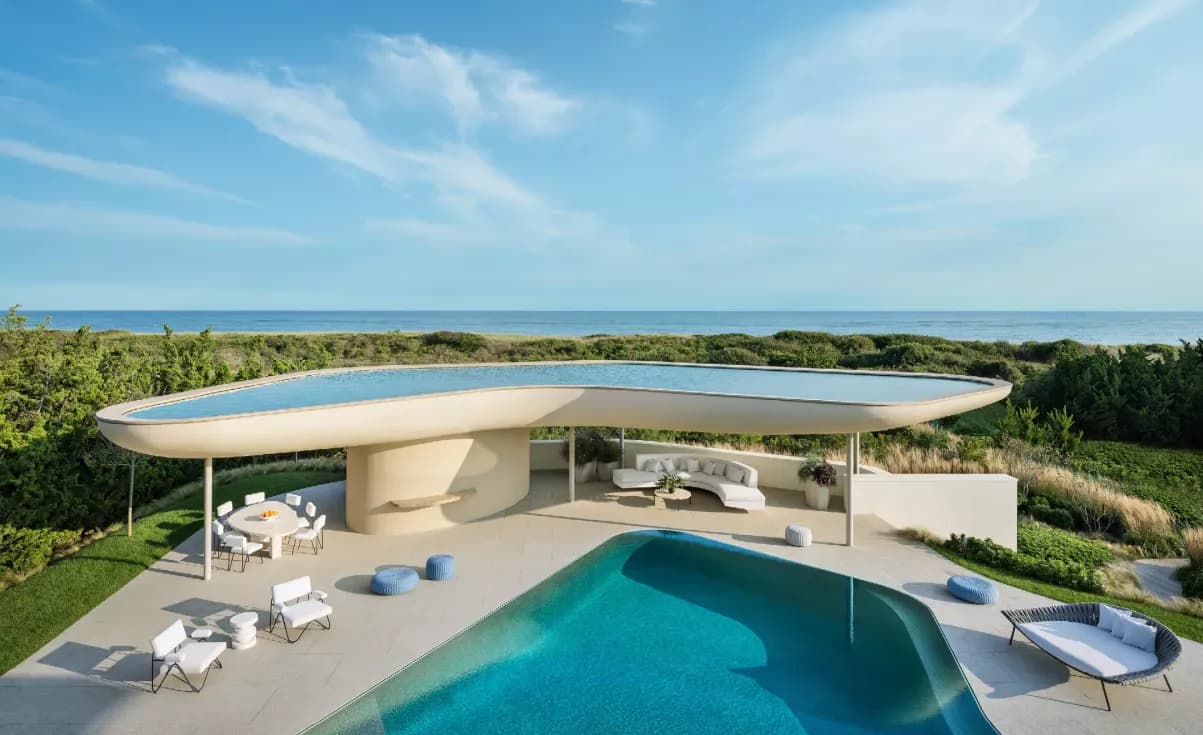 Curved modernist residence with pool overlooking coastal landscape, featuring smooth concrete forms and expansive glazing by Steven Harris Architects.
