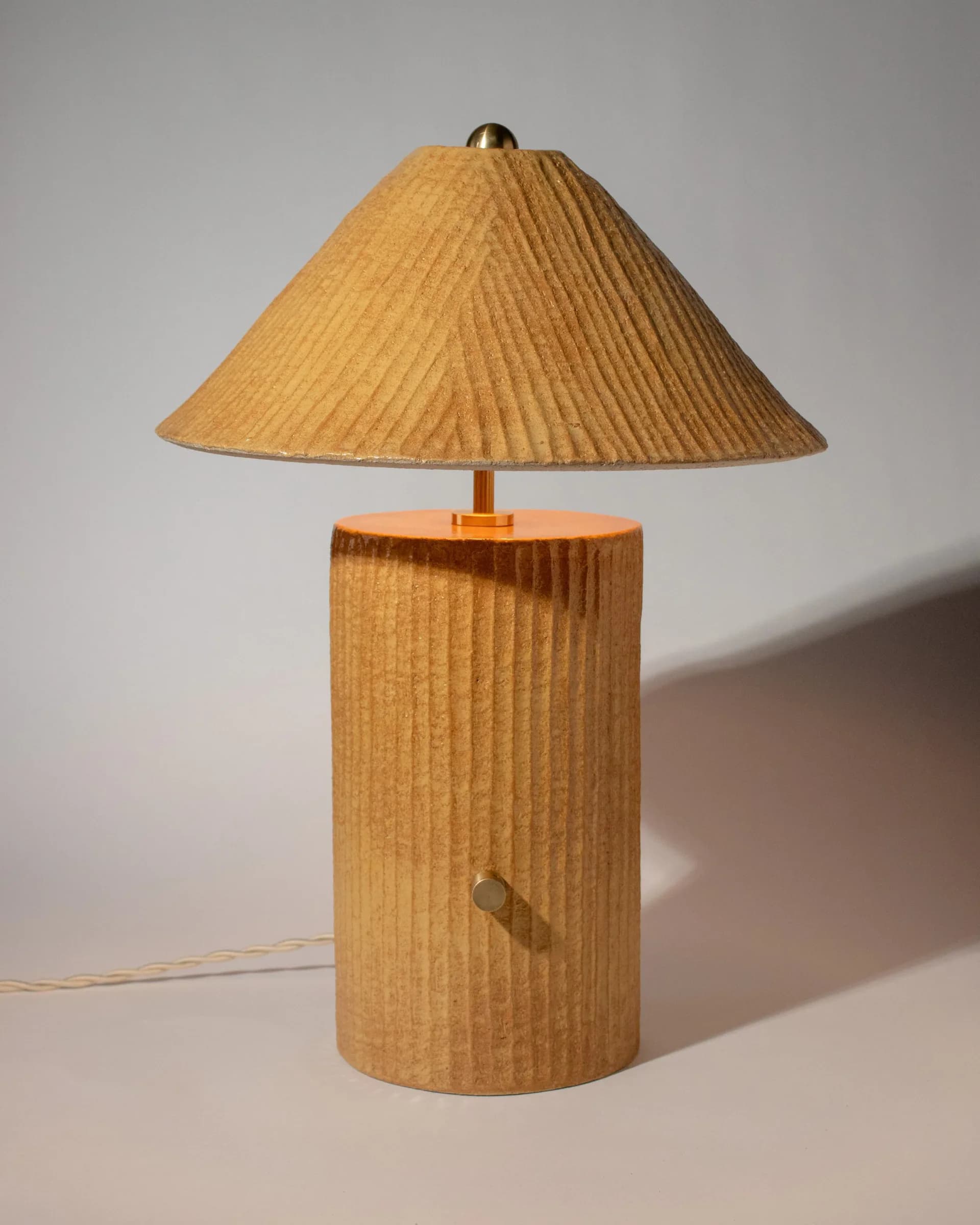 Wooden table lamp with cylindrical base and large conical shade in natural wood tones with vertical grain detailing by Streicher Goods.