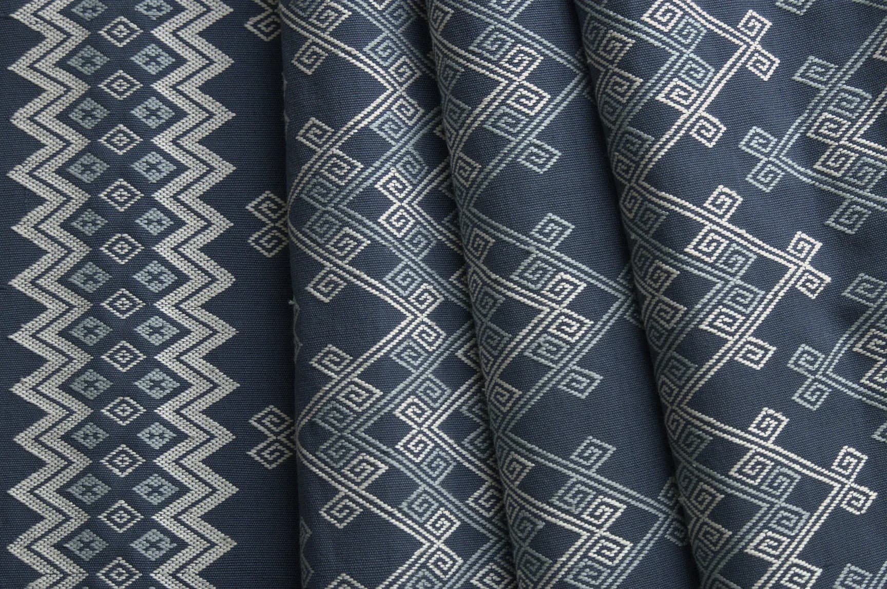Four rolls of patterned fabric in dark gray with geometric designs in white and silver tones by Studio Four NYC.