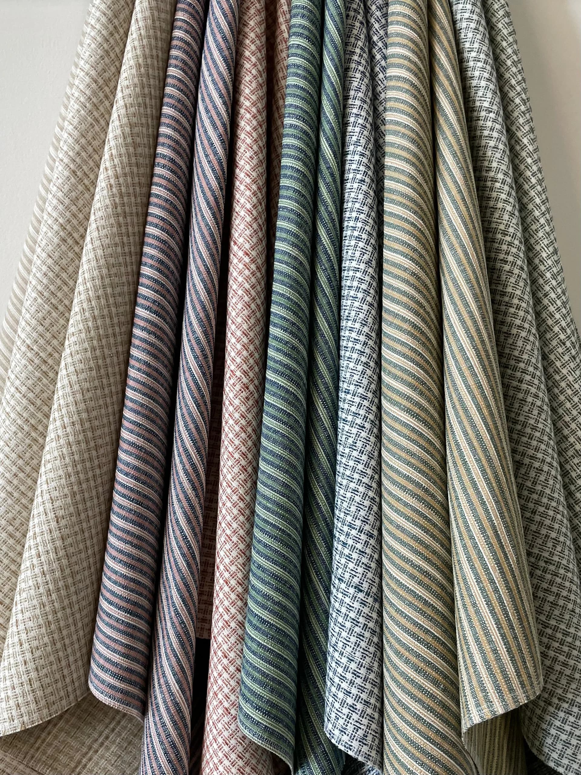 Draped fabric swatches in neutral and muted tones display various weave patterns and textures, showcasing material selection by Studio Four NYC.