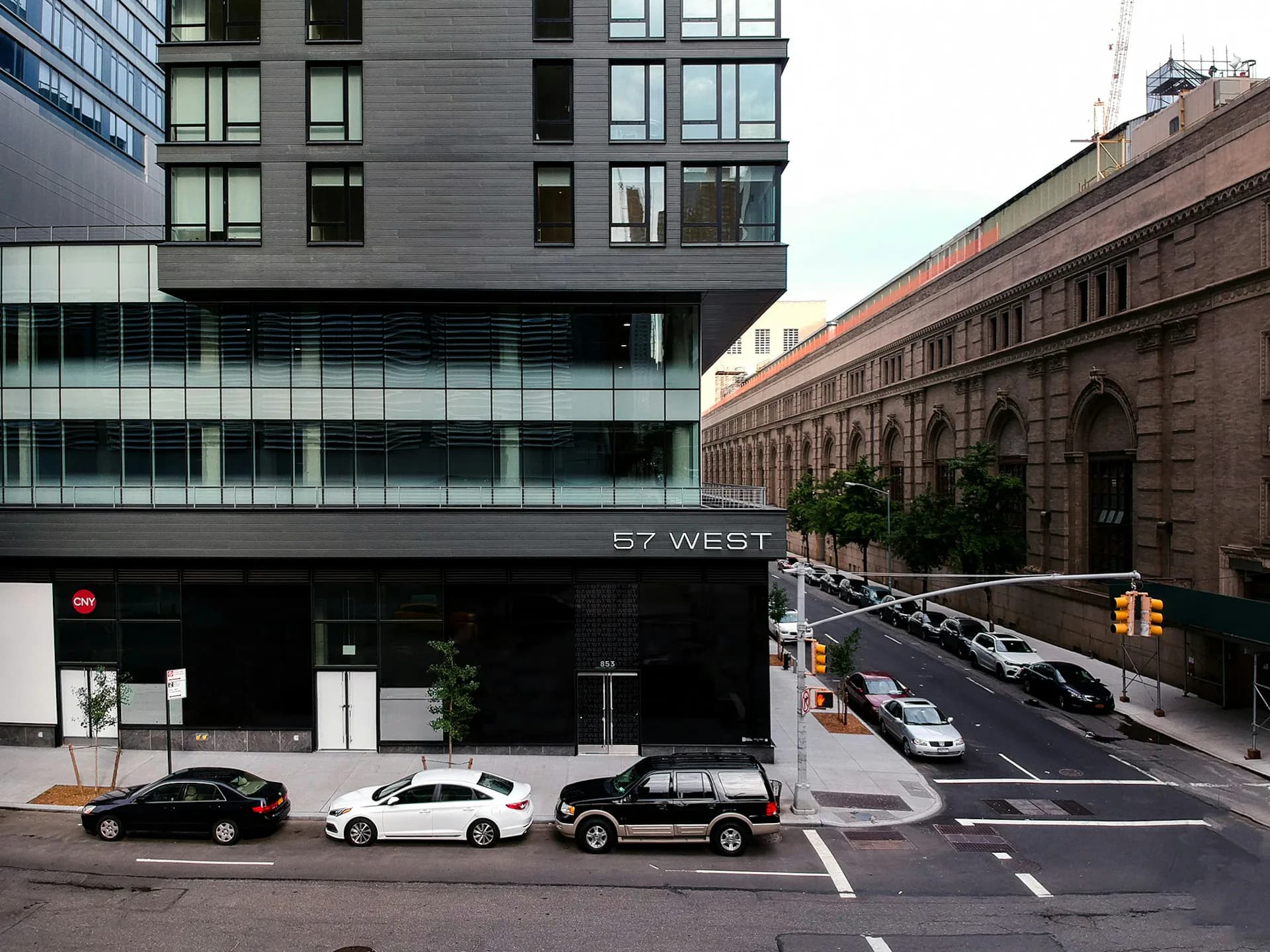 Modern mixed-use building with dark facade and street-level retail at 57 West, featuring contemporary architecture adjacent to historic brownstone, designed by STUDIO V.