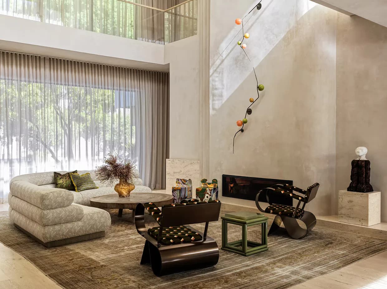 Luxury living room with curved cream sectional, black sculptural furniture, and hanging kinetic mobile installation by SuperStrata.