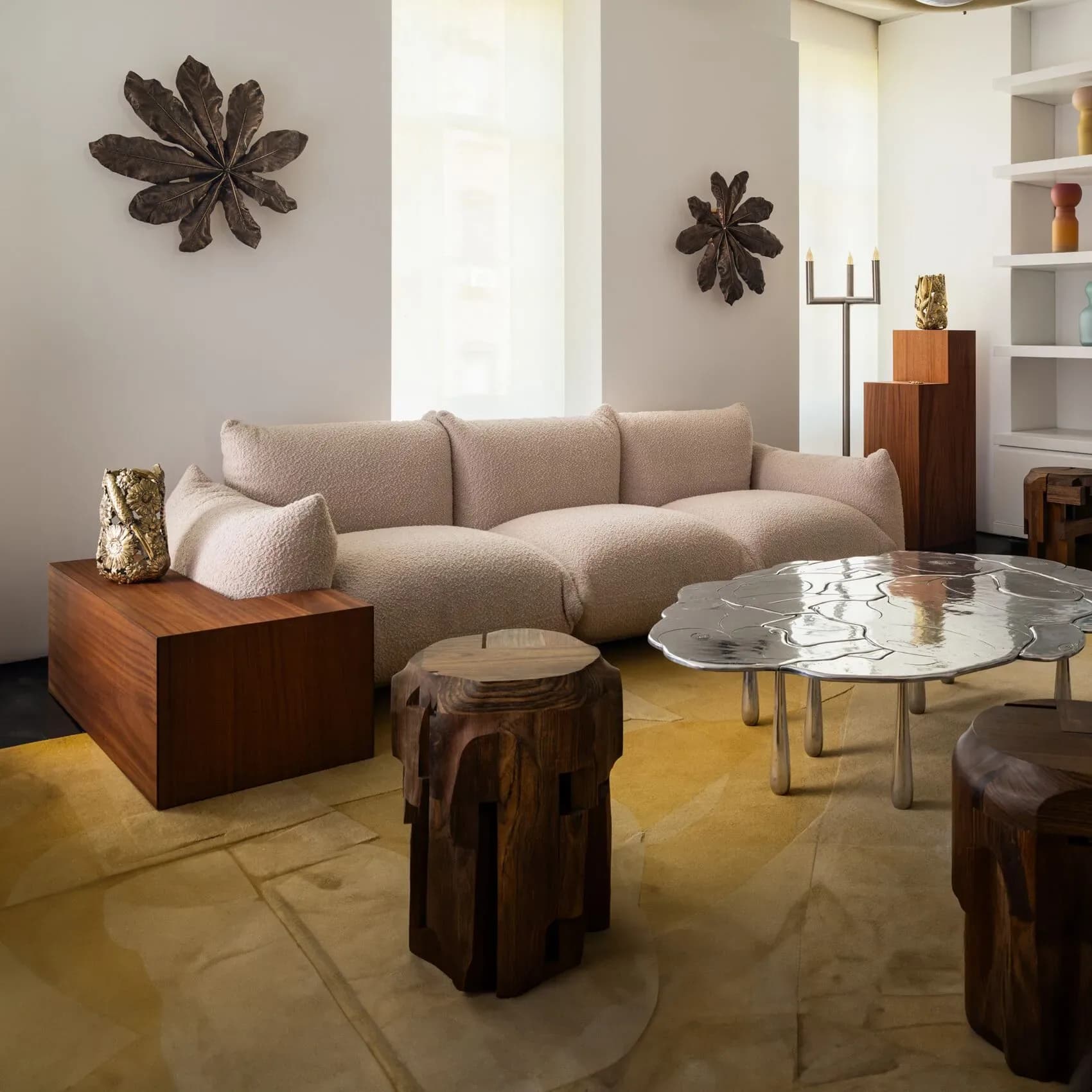 A sculptural living room with curved beige sofa, organic wood elements, and polished concrete flooring by The Future Perfect.