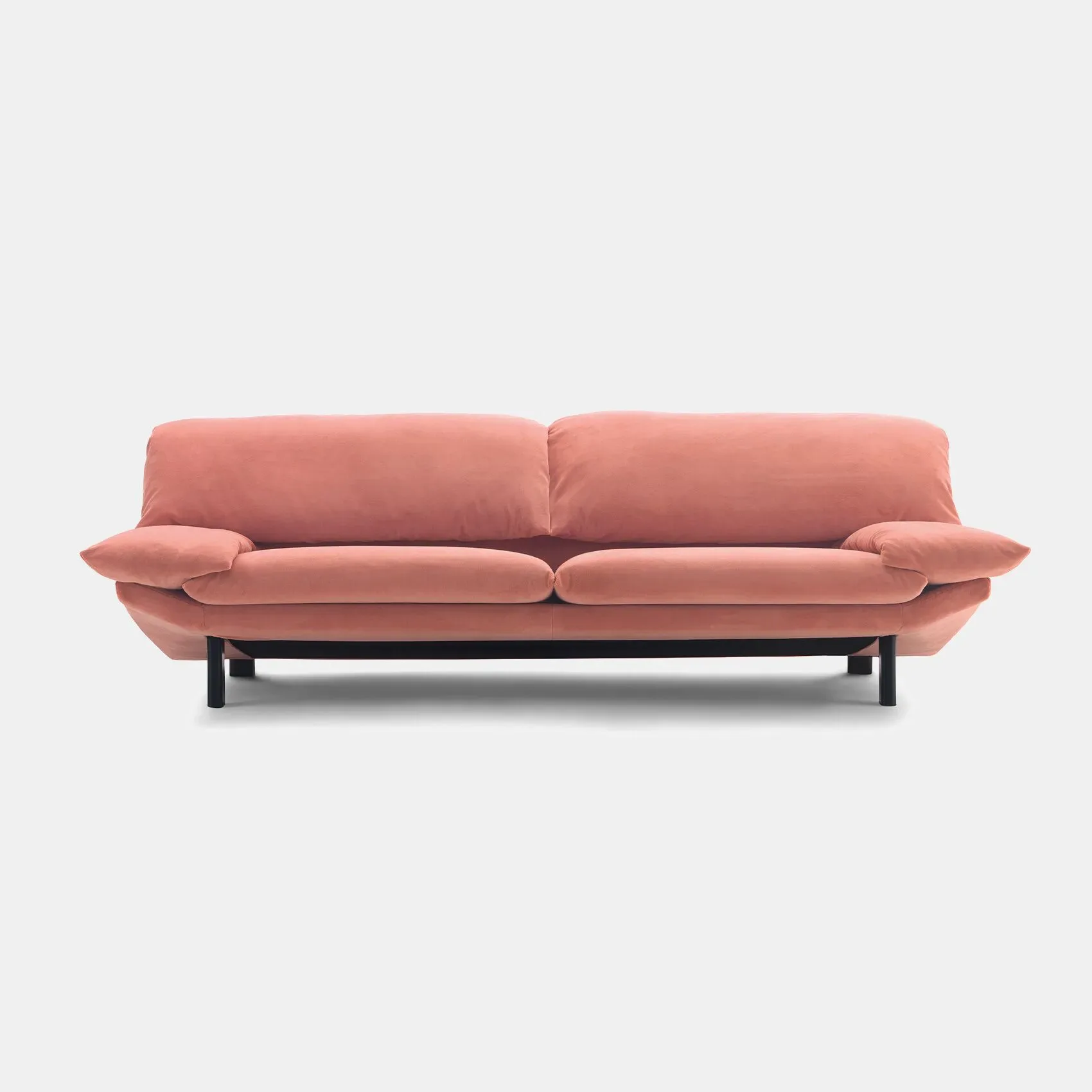 A coral-pink upholstered sofa with curved armrests and black metal legs, shown against a neutral background by The Future Perfect.