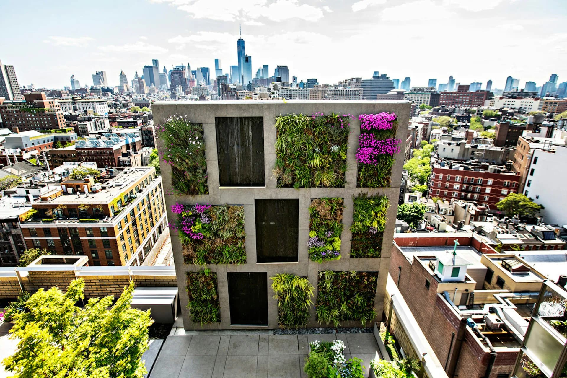 Modern rooftop garden installation with living green walls integrated into concrete grid structure overlooking NYC skyline, by Tinmouth Chang Architects.