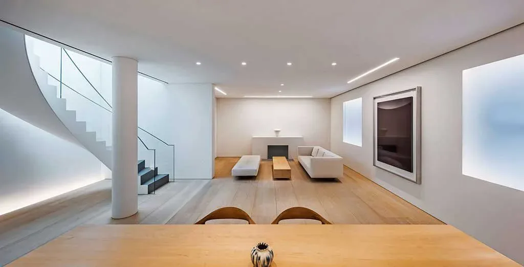 Modern office interior with wooden flooring, white walls, glass staircase, and minimalist furnishings by Tirschwell & Co.