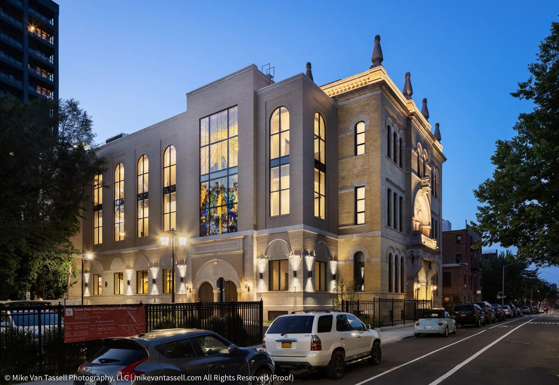 Illuminated historic brick building with arched windows and stone detailing, photographed at dusk by TPD Architecture.