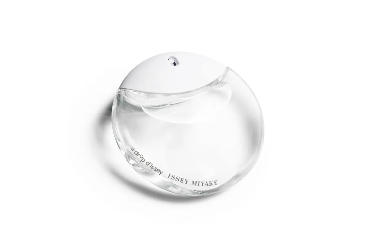 A translucent spherical fragrance bottle with minimalist design and subtle branding text, photographed against a white background by Todd Bracher Studio.