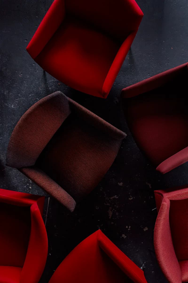 Red and burgundy fabric upholstered furniture pieces arranged on dark surface, showcasing textile design and form by Todd Bracher Studio.