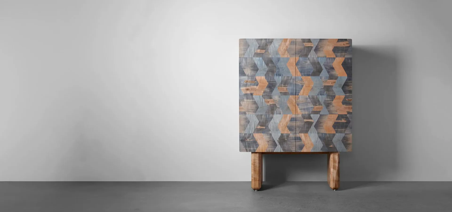A geometric patterned upholstered cabinet with wooden legs in blue and orange tones against a neutral background by Token.