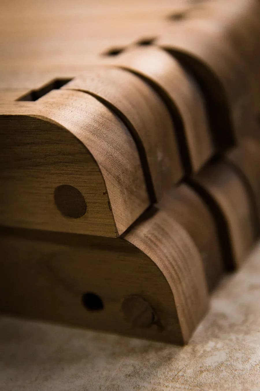 Wooden architectural model or decorative object with curved leather straps and brass details, showcasing craftsmanship and material exploration by Token.