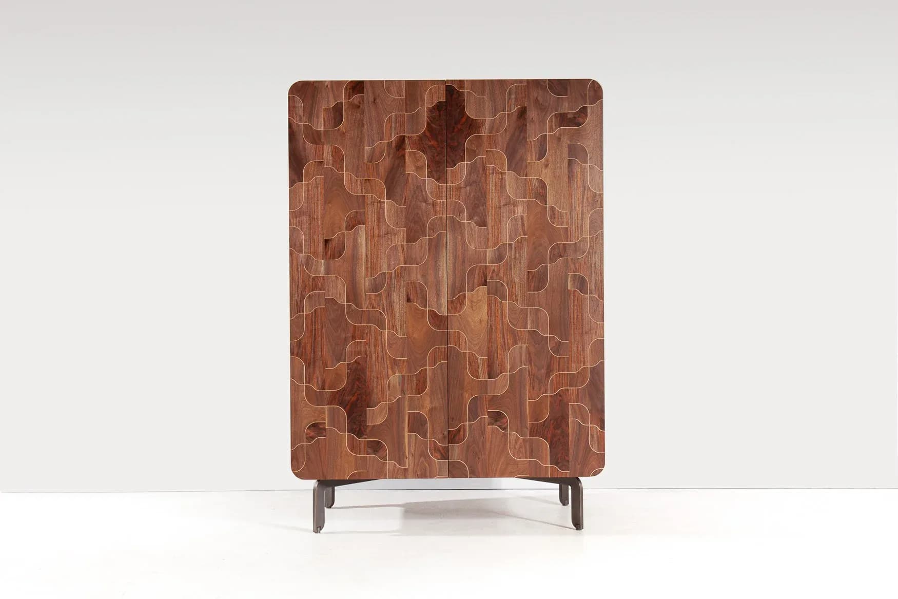 Wooden cabinet with geometric parquet pattern in warm brown tones, featuring tapered legs, photographed against a neutral background by Token.