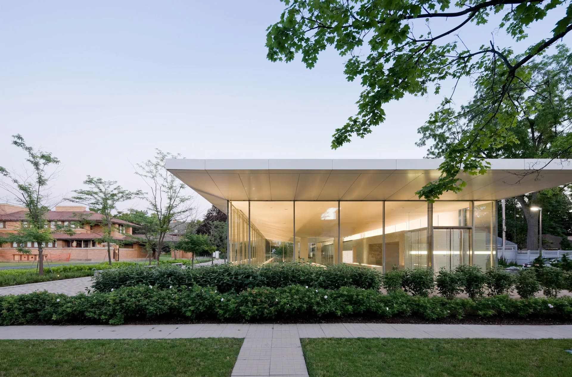 Modern glass pavilion with open interior, metal frame, and minimalist design set in a landscaped garden setting by Toshiko Mori Architect.